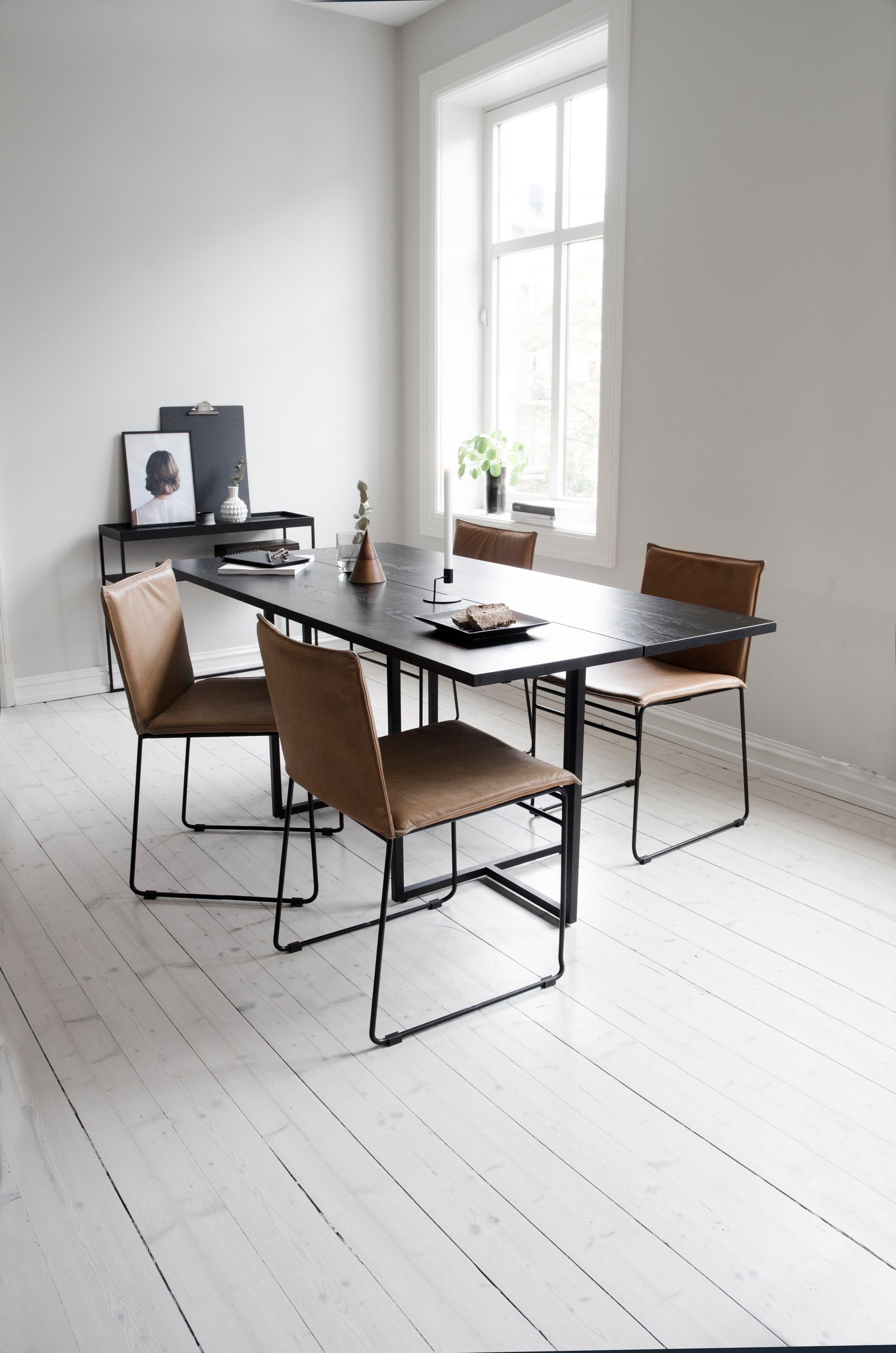 Kyst spisestoler med vintage cognac outer rundt et sort oljet T-bordet spisebord